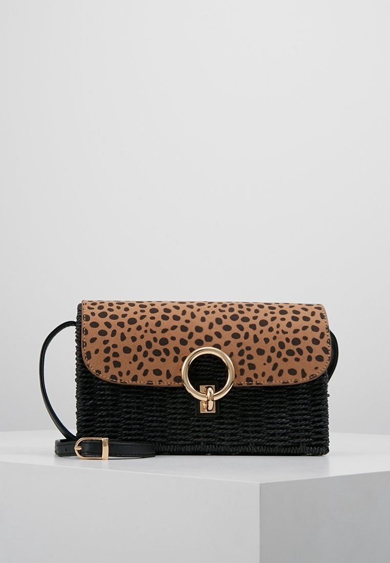Sac à main noir tissé avec un rabat en imprimé léopard, fermeture à anneau en métal doré et une bandoulière noire amovible. Matériaux texturés sur l'ensemble.
