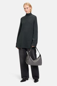 Maglione a maglia di colore verde scuro, oversize, con colletto alto, abbinato a jeans neri larghi e una borsa grigia curvata. Presenta maniche lunghe e un motivo strutturato.