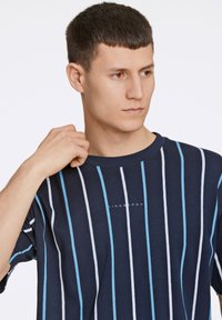 Marineblauwe gestreepte t-shirt met lichtblauwe en witte verticale strepen, korte mouwen en een ronde halslijn met een merklogo in het midden.