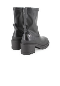 Botas de tobillo de cuero negro con puntera cuadrada, tacón robusto, cremallera lateral y tiradores para facilitar su uso. Suela de goma texturizada para mayor agarre.