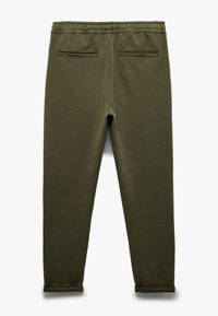 Olivengrønne sweatpants med en struktureret stof, elastisk talje og to baglommer. Har tætsiddende ben og ribkantede afslutninger.
