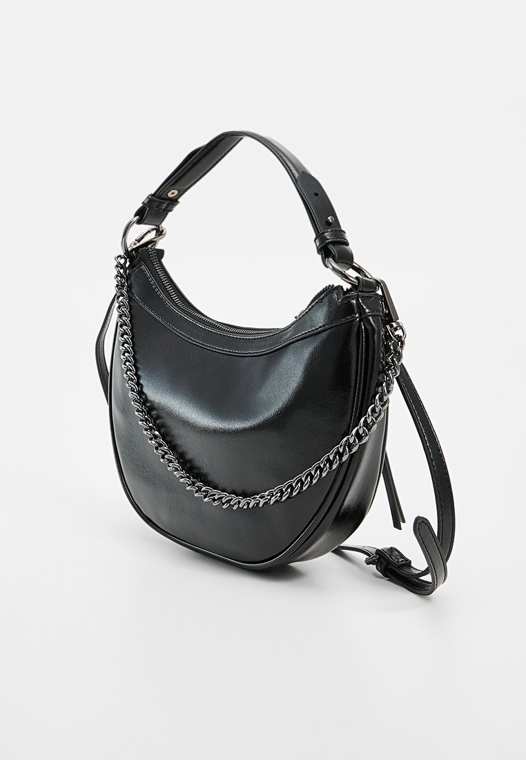 Schwarze Leder-Umhängetasche mit geschwungener Form, Kettenakzent-Tragegurt, Reißverschlussverschluss und glatter Textur. Verstellbarer langer Gurt inklusive.