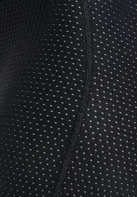 Schwarzer Sportbekleidungsstoff mit einem strukturierten, durchlässigen Design, das kleine, gleichmäßig verteilte Löcher und sichtbare Nahtdetails aufweist.