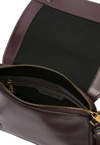 Bordowa skórzana torba z złotymi akcesoriami, z zamykaną na zamek kieszenią, czarną podszewką oraz gładką powierzchnią z klapą.