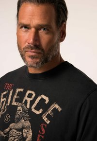 Černá bavlněná mikina s kulatým výstřihem, která má velký grafický potisk svalnaté postavy a tučné písmo v opotřebované smetanové a červené barvě.