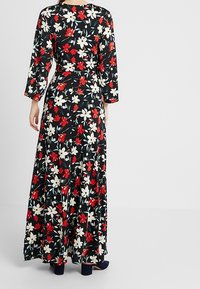 Maxiklänning i lätt, blommönstrad tyg med röda och vita blommor på svart bakgrund, långa ärmar och cinchad midja.