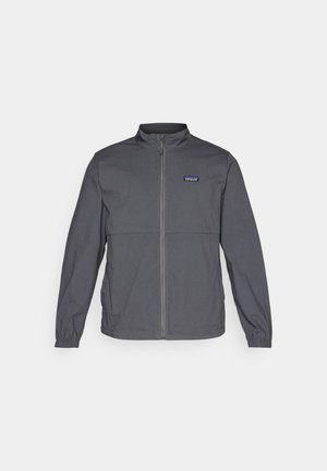 Gray lightweight jacket with a high collar, full front zipper, elastic cuffs, and a logo patch on the upper left chest. Smooth fabric texture.