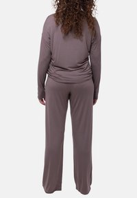 Brun långärmad topp med avslappnad passform och rundad rygg, ihop med matchande vida byxor, tillverkade av mjuk, stretchig tyg.