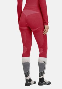 Rote thermische Leggings und knielange Socken. Die Leggings haben eine strukturierte Oberfläche mit nahtloser Verarbeitung; die Socken haben ein grau-weißes geometrisches Muster.