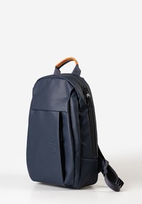 Marineblaue Tasche aus glattem synthetischem Material mit einem oberen Griff, einer Front-Reißverschlusstasche und verstellbaren Trägern. Dezente Markenkennzeichnung an der Seite.