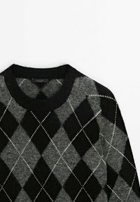 Pull en argyle noir et gris avec un col rond, présentant une texture douce et des coutures blanches soulignant les losanges.