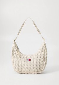 Cream-colored quilted handbag with a rounded shape, featuring a zip closure and an adjustable strap. Logo patch visible on the front.