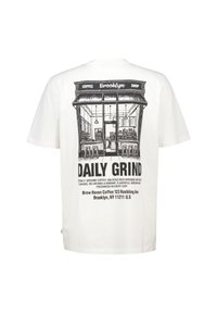 Camiseta de algodón blanca con una ilustración gráfica negra de la fachada de una cafetería y el texto "DAILY GRIND" con detalles de ubicación debajo.