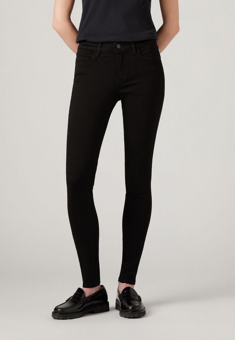 Zwarte skinny jeans van denim, met een slim fit en een standaard taille. Voorzien van zijzakken en een knoopsluiting. Glad materiaal.