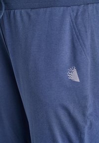 Navy blue sweatpants made of soft fabric, featuring an elastic waistband with a drawstring, side pockets, and a white geometric logo detail.