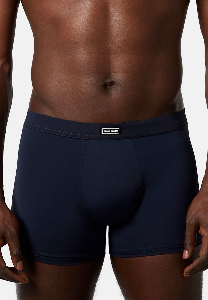 Dark blue fitted boxer shorts made of smooth fabric, featuring a branded elastic waistband and a structured pouch design.