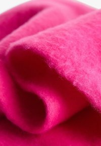 Filc v svetlo roza barvi, ki se ponaša z mehkimi teksturami in plastmi, z enotno barvo brez vzorcev ali dodatkov.