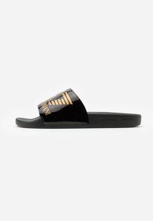 Sandalia tipo slide negra con una amplia tira brillante que presenta un logo dorado de Emporio Armani y suela plana.