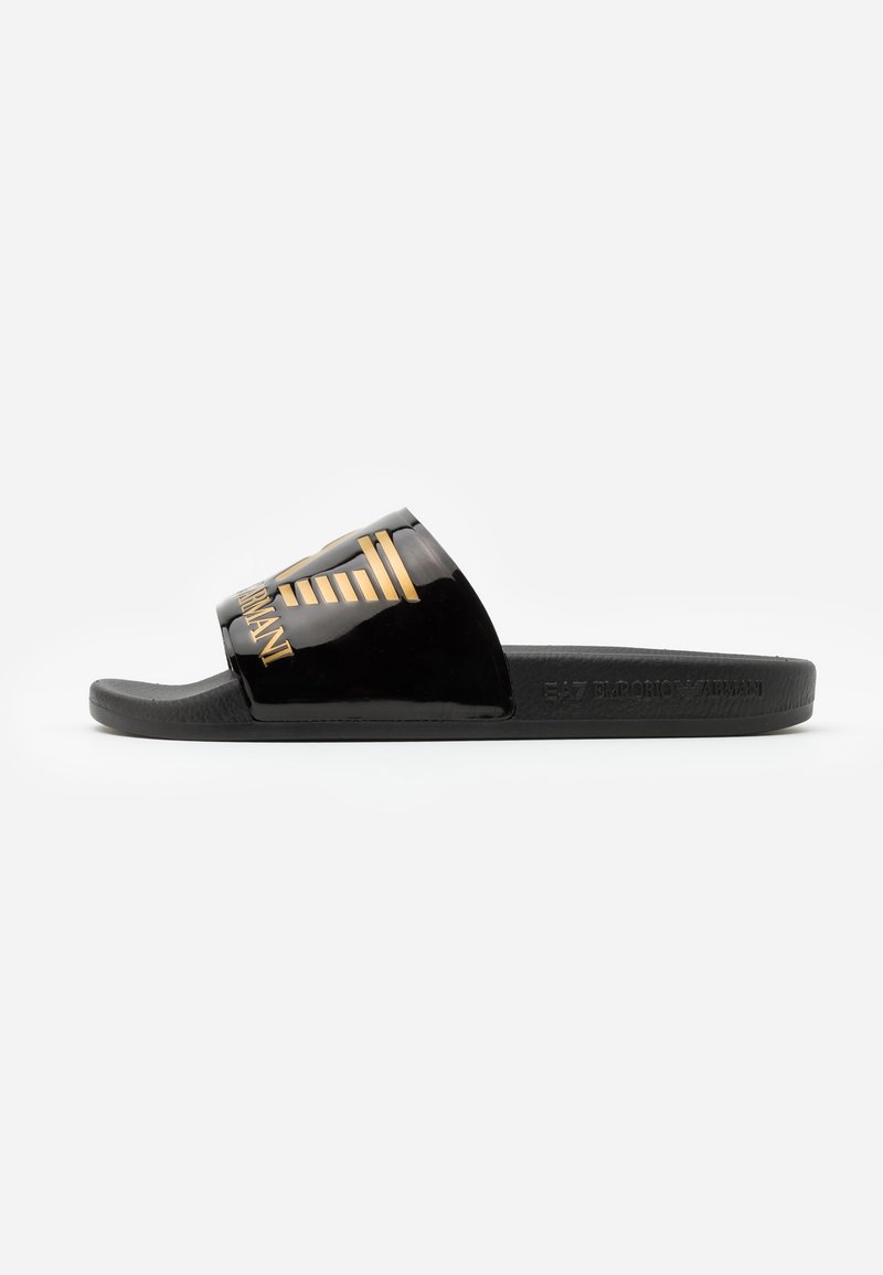 Sandale slide noire avec une large bride brillante ornée d'un logo Emporio Armani doré et une semelle plate.