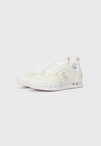 White athletic shoes with mesh panels, gold accents, and a textured rubber sole. Features laces and a reinforced heel tab.