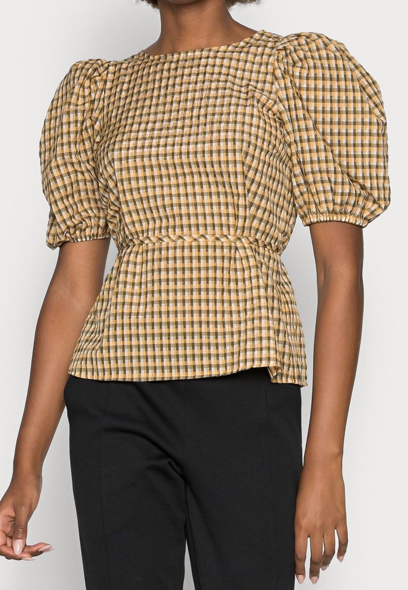Blusa gialla e marrone a scacchi con maniche a sbuffo, vita aderente e design a peplum. Realizzata in tessuto leggero con una finitura testurizzata.