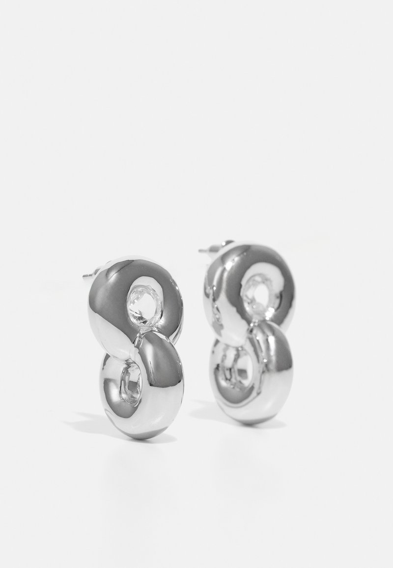 Silvermetallörhängen med en skulptural dubbelringdesign med en blank finish och en liten klar stens accent.