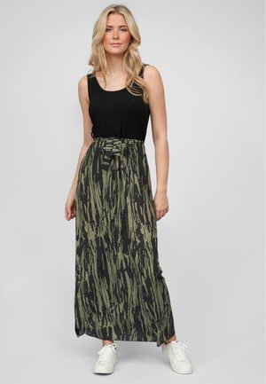 Maxi dress with a black, sleeveless top and a flowing, patterned skirt in green and black tones. Features a tied waist detail and white sneakers.