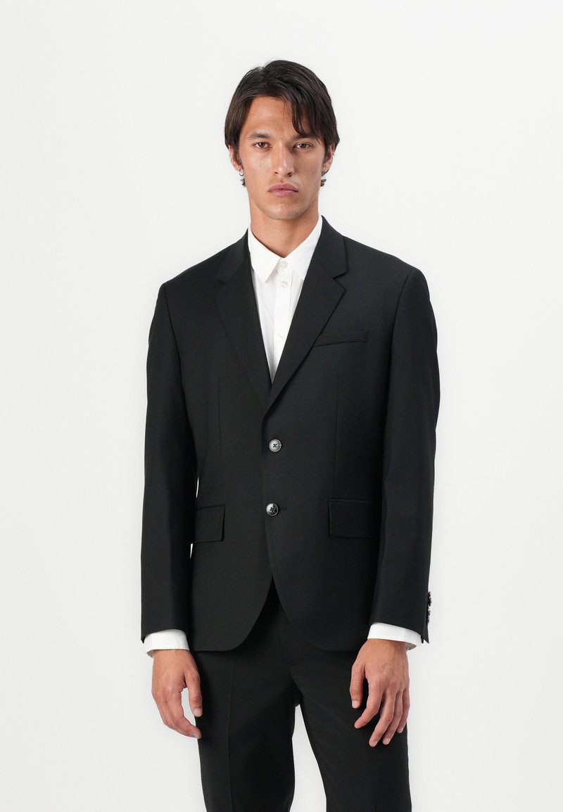 Black tailored suit jacket, made of smooth fabric, featuring two buttons, notch lapels, and a single chest pocket. White shirt visible underneath.