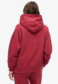 Oversizowa bordowa bluza z dużym kapturem, żebrowanymi mankietami i dołem. Wykonana z miękkiego materiału, charakteryzuje się luźnym krojem i minimalistycznym wykończeniem.