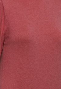 Kortärmad topp i en strukturerad, mörkröd tyg. Har en rund halsringning med en jämn och slät stickning. Inga synliga mönster eller detaljer.