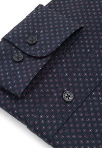 Granatowa koszula z długim rękawem z małym różowym i niebieskim wzorem kwiatowym, czarne guziki z wygrawerowaną nazwą marki, starannie złożona.