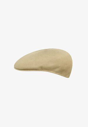 Cappello beige stile berretto, realizzato in tessuto testurizzato, con una parte superiore liscia e arrotondata e una visiera leggermente stretta nella parte anteriore.