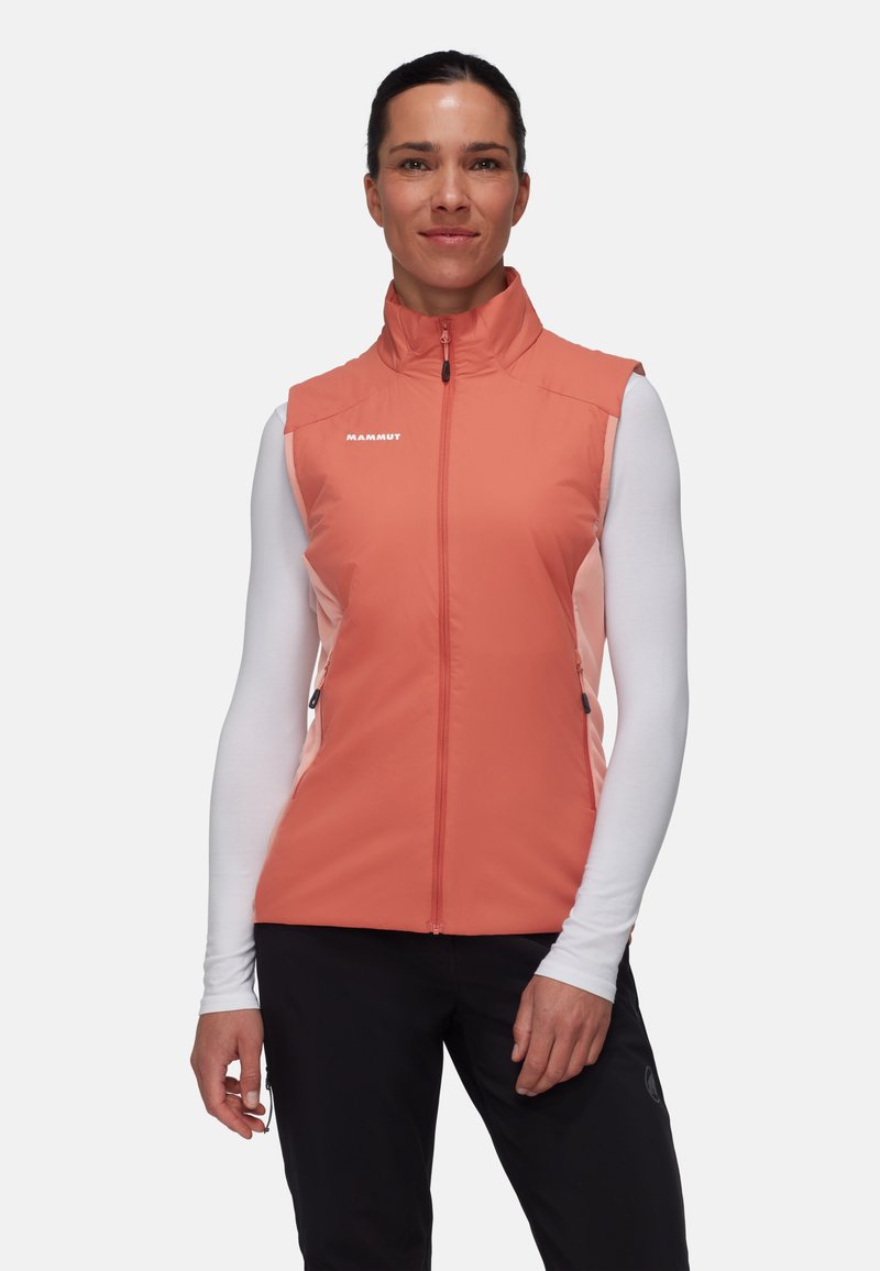 Roze mouwloze vest met ritssluiting, heeft zijzakken, contrasterende stoffenpanelen en een logo op de borst. Gemaakt over een top met lange mouwen.