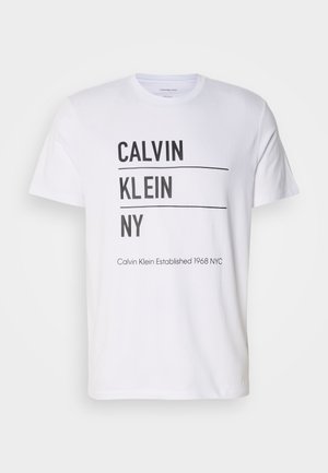 Camiseta blanca con el texto negro "CALVIN KLEIN NY", con dos líneas horizontales y el texto adicional "Calvin Klein Established 1968 NYC" en la parte inferior.