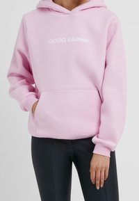 Felpa con cappuccio rosa realizzata in morbida miscela di cotone, con una tasca frontale e scritta bianca "GOOD KARMA". Polsini e orlo a costine per una vestibilità aderente.