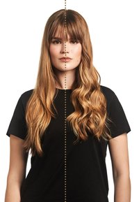 Jonge vrouw met lang blond haar, half steil en half golvend, gekleed in een zwart shirt, die recht vooruit kijkt met een gestippelde lijn die haar gezicht en haar scheidt.