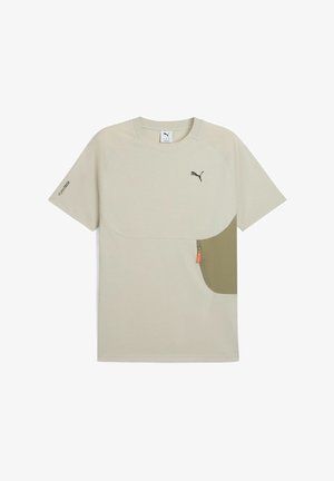 Gaišais bēšs īsām piedurknēm T-krekls ar lielu olīvu zaļa kabatu un mazu rāvējslēdzēja detaļu. Izgriezumā ir melna logo.