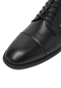 Black leather dress shoe with a rounded toe, lace-up design, and minimal stitching. Features a smooth surface and a rubber sole.