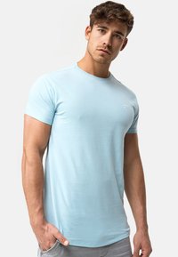 Camisa de tirantes corta de color azul claro en una tela suave, con un cuello redondo y un pequeño logo en el pecho. Ajuste estándar.