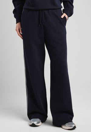 Pantalons de survêtement bleu marine avec une taille élastique et un cordon de serrage, dotés de poches latérales et de rayures blanches le long des coutures extérieures.