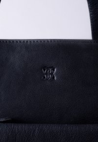 Black leather bag featuring a textured surface and embossed logo. Stitching is visible along the edges, adding detail to the design.