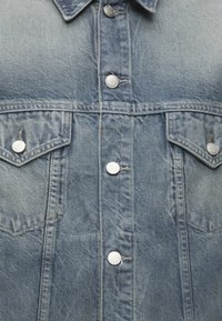 Ανοιχτό μπλε denim μπουφάν μπροστά με ασημένια κουμπιά και δύο τσέπες στο στήθος με καπάκια και κουμπώματα.