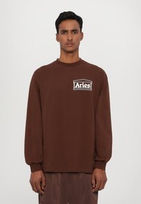 Brun langærmet sweatshirt med et hvidt "Aries" logo på brystet, lavet af bomuld med en afslappet pasform og ribbede manchetter.