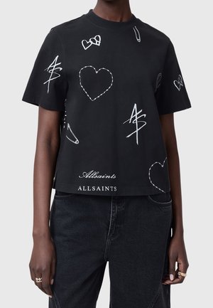 T-shirt en coton noir avec des motifs graphiques blancs, comprenant des cœurs et des symboles, avec une coupe courte et le logo "Allsaints" au bas.