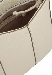 Borsa a mano in pelle crema con una forma strutturata, superficie testurizzata e accenti marroni a contrasto; presenta un cordoncino e un scomparto interno con zip.