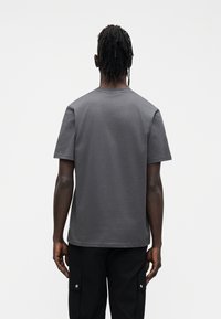 Ciemnoszary t-shirt wykonany z miękkiego materiału, z krótkimi rękawami i okrągłym dekoltem, o prostym kroju i minimalistycznym wzornictwie.