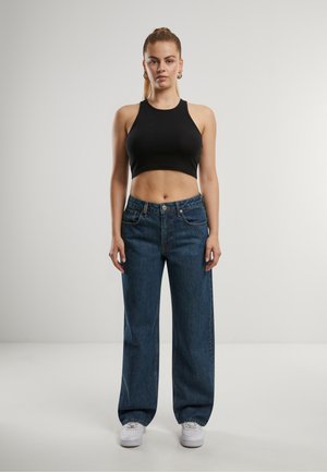 Schwarzes, geripptes Croptop kombiniert mit hochgeschnittenen, blauen weit geschnittenen Jeans. Verfügt über klassisches Fünf-Taschen-Design, Knopfverschluss und weiße Sneakers.