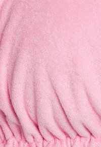 Tecido de toalha rosa com uma textura suave, apresentando uma seção franzida na parte de baixo. Superfície lisa e macia com uma cor consistente.