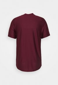 Camiseta de manga corta burdeos con un sutil estampado de cuadrícula en la parte trasera, fabricada en un tejido ligero y transpirable. Cuello redondeado.