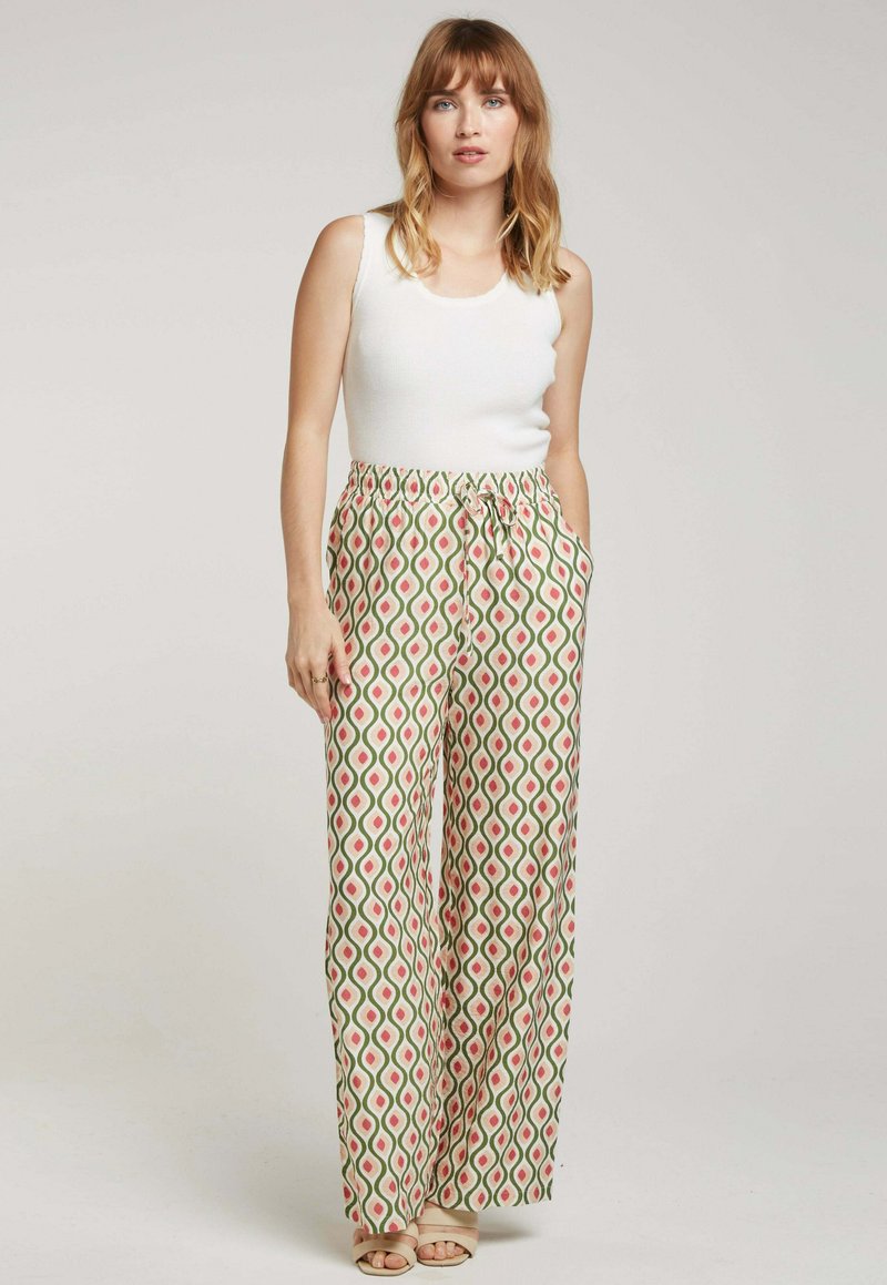 Pantalons à jambes larges à motif en vert, rouge et crème. Taille élastique avec cordon de serrage. Tissu lisse et design géométrique. Mélange de coton.